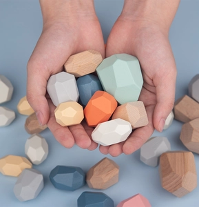 Close-up of hand holding colorful wooden balancing stones for educational stacking play