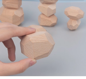 Close-up of hand holding natural wooden balancing blocks showing geometric gemstone shapes