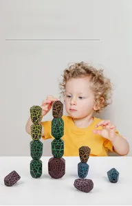 Close-up of child stacking colorful irregular polyhedron blocks with unique crackle patterns