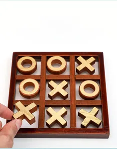 Detail of hand placing wooden Tic-Tac-Toe pieces on a smooth polished solid wood board