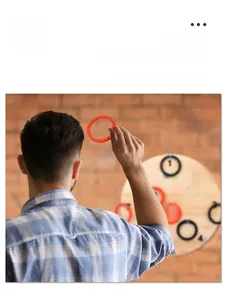 Action shot of throwing a red ring at a numbered wooden wall-mounted hook game board