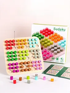 Detail showing wooden Sudoku board, colorful numbered cylinders, and manual on pink background