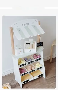 Detailed view of a wooden toy market stall featuring a play cash register and fruit set