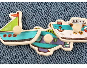 Detail of wooden peg puzzle pieces featuring a sailboat, submarine, and steamship
