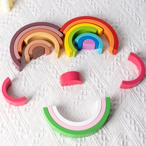 Educational wooden rainbow stacking blocks arranged in a smiley face on a white knit background