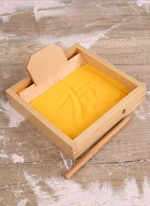Close-up of Montessori wooden sand tray with yellow sand and writing tools for kids