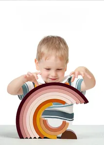 Detail showing a toddler playing with 10-tier wooden rainbow stacking blocks for early education
