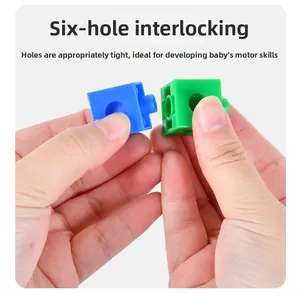 Macro detail of hands connecting 6-hole interlocking plastic building blocks for kids