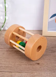 Detail of wooden rolling rattle with colorful balls on a textured wood floor surface