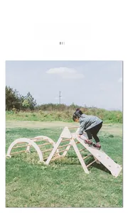 Detail of wooden climbing triangle set with slide and arch on outdoor grass