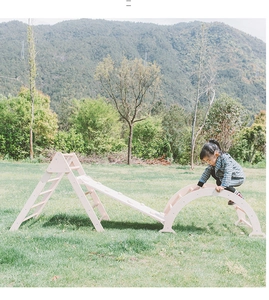 Detail of wooden indoor climbing triangle set with slide and arch on a green lawn
