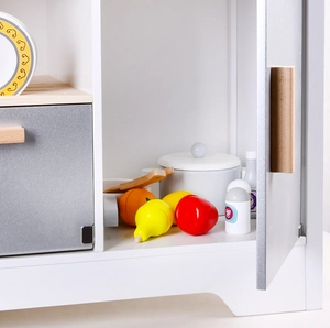 Close-up of wooden toy kitchen cabinet with realistic fruit accessories and small pots
