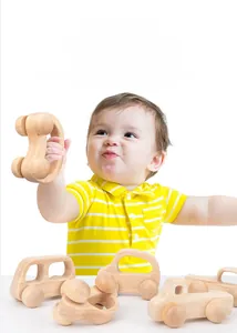 Bébé saisissant une voiture en bois naturel pour l'entraînement de la motricité