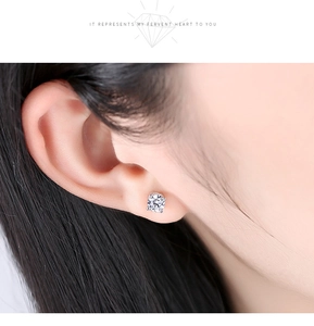 Close-up of 925 sterling silver four-prong stud earring on ear with round cut diamond