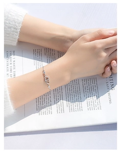 Macro shot of silver intertwined heart bracelet with sparkling stones on a magazine