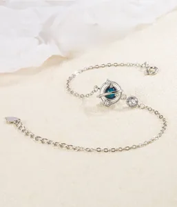 Détail du bracelet planète en argent S925 avec pierre bleue sur fond de sable fin