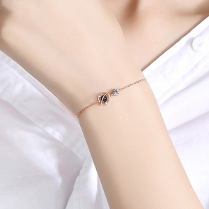 Détail du bracelet planète or rose avec cristaux noirs et zircon sur poignet femme