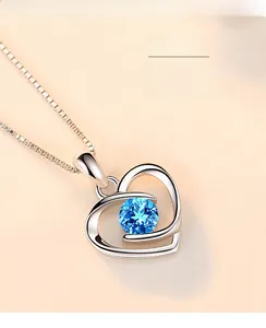 Detail of heart pendant necklace with natural blue topaz and silver box chain