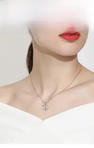 Close-up of a silver heart necklace with a round pink zircon on a model's collarbone