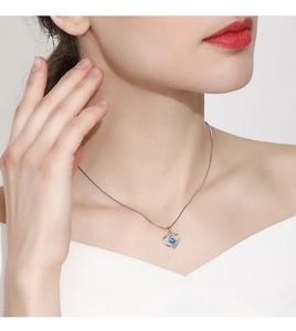 Detailed view of sterling silver heart pendant necklace with blue gemstone on model