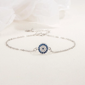 S925 sterling silver evil eye bracelet with blue and white stones on a beige base