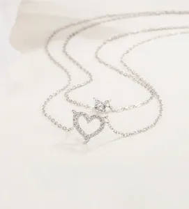 Detail of layered necklace featuring a sparkling zircon heart pendant and solo diamond stud