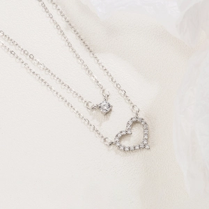 Silver double layer necklace with rhinestone heart pendant and zircon stone on cream background
