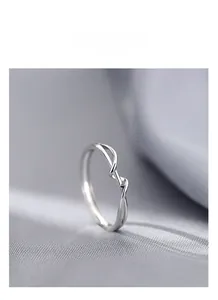 Dettaglio dell'anello ritorto in argento S925 minimalista su sfondo di seta azzurra
