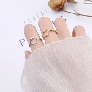 Detail of silver and gold wishbone V-shaped adjustable rings on model's hand