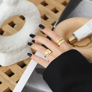 Detail of irregular textured gold rings set with hammered surface on model hand