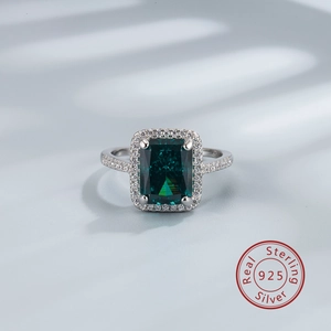 Détail macro d'une gemme verte taille émeraude sur une bague halo en argent 925