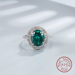 Detail of 925 sterling silver ring with oval green stone and halo diamonds in soft light