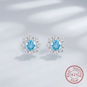 Détail de boucles d'oreilles fleurs en argent 925 avec gemmes bleu clair et petits diamants