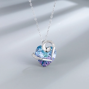 Detailed close-up of heart-shaped gradient crystal pendant with swan-inspired silver metal
