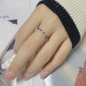 Detail of colorful rainbow zircon stones set in a thin silver band on woman's finger