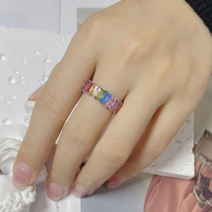Close-up of a silver ring with rectangular rainbow gradient gemstones on a white stone