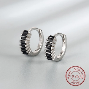 Gros plan sur des boucles d'oreilles en argent 925 avec pierres noires sur de la soie