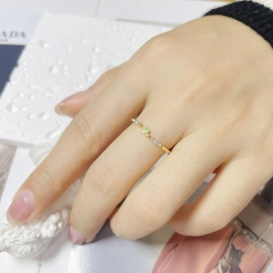Macro shot of thin gold band with colorful rainbow zircons on a hand with artistic props