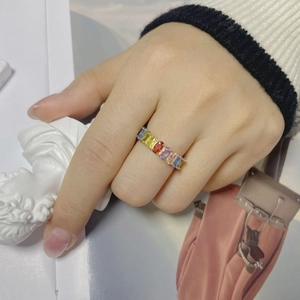 Vue détaillée d'une bague dorée de luxe avec zircons arc-en-ciel taille baguette au doigt