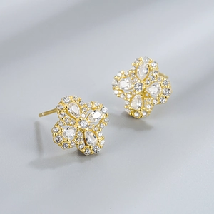 Macro detail of gold flower earrings with drop-shaped zircons and center diamond setting