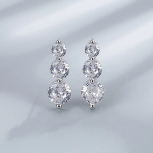 Detailed view of sterling silver three-stone gradient earrings on silk fabric
