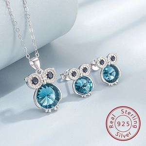 Détail macro de parure chouette en argent S925 avec collier et boucles en cristal bleu