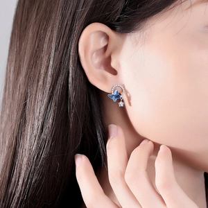 Macro detail of S925 silver butterfly earrings with blue crystal and small star charm