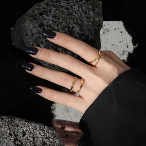 Detailed close-up of double-layer crossed gold rings on model fingers with dark background
