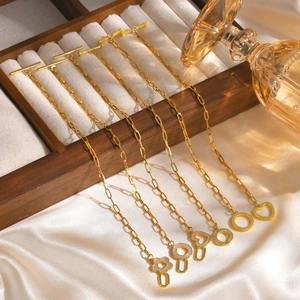 Close-up of gold paperclip link bracelets featuring heart and flower charms with T-bar clasps