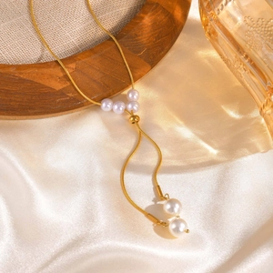 Détail d'un collier chaîne serpent dorée en Y avec cinq perles blanches sur soie blanche