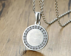 Macro shot of silver stainless steel pendant with pavé cubic zirconia and engraved Chinese character