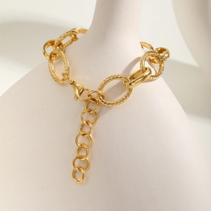 18K gold plated interconnected link bracelet with textured rings on ceramic vase