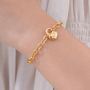 Gros plan d'un bracelet en acier inoxydable doré 18 carats avec serrure en cœur au poignet