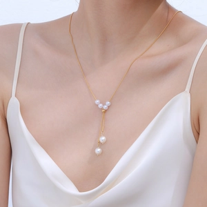Gros plan d'un collier en Y doré en acier inoxydable avec d'élégantes perles sur un mannequin
